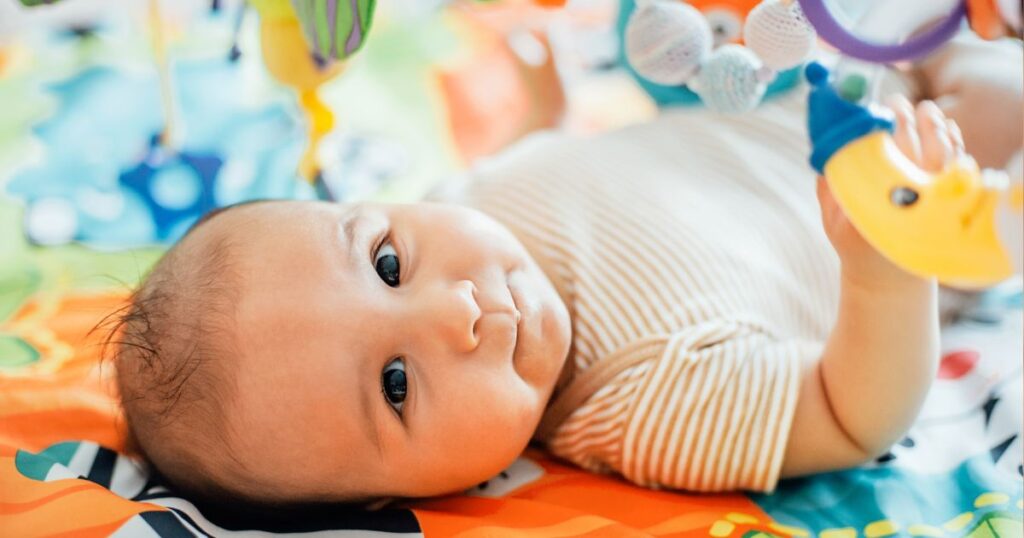 bébé dans lit parapluie avec des jouets