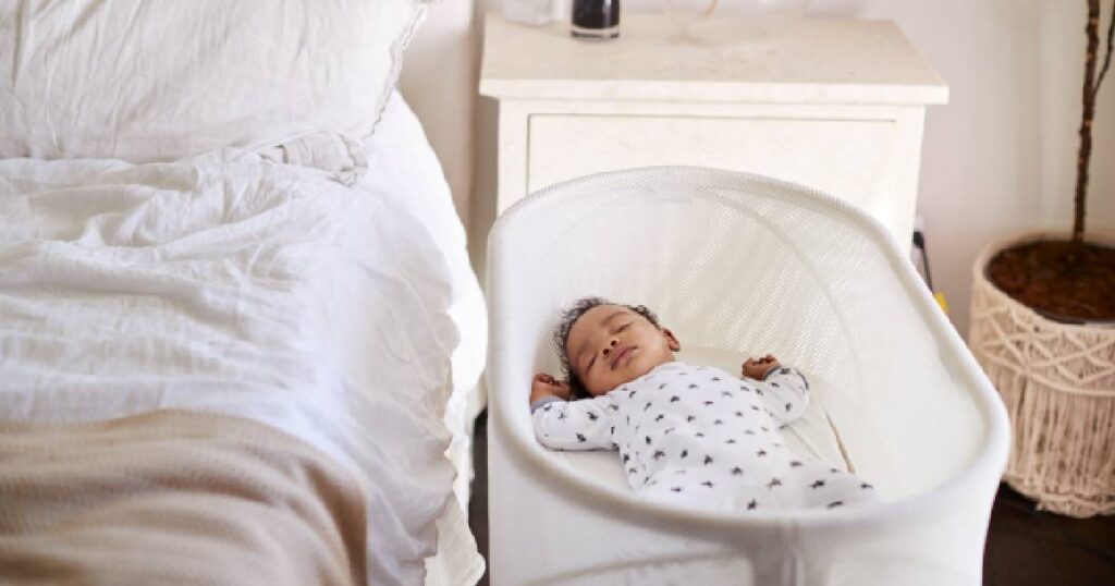 bébé de 3 mois dans son berceau à coté du lit