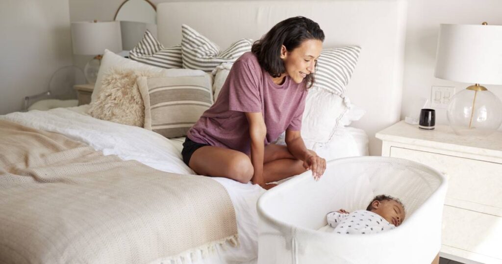 maman regardant son bébé dans un lit parapluie cododo